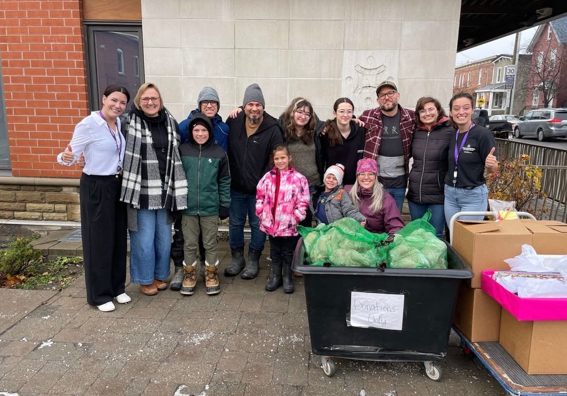 Group of people with a bin of groceries outside a building