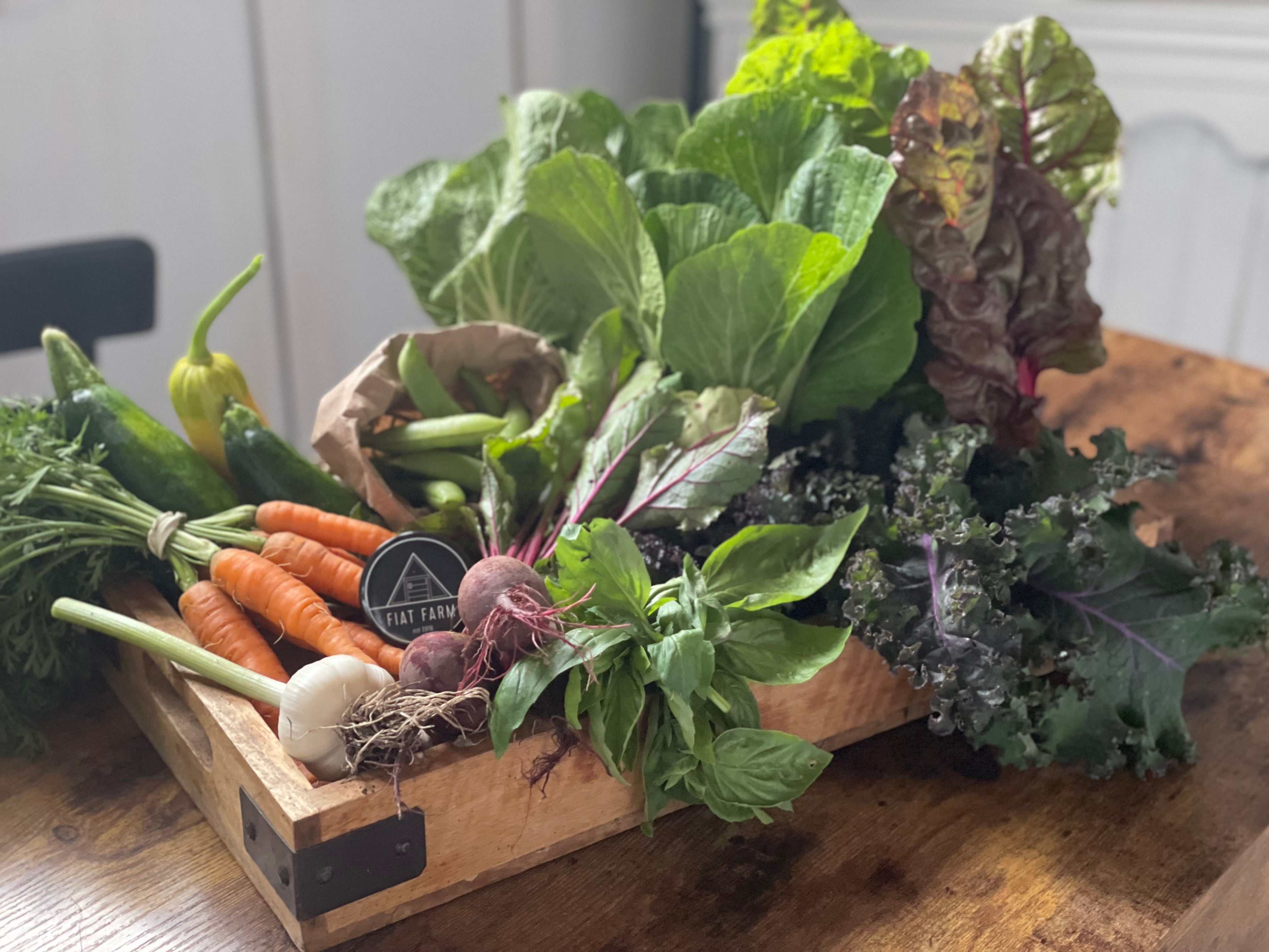 Assorted fresh vegetables in a wooden box on a wooden surface