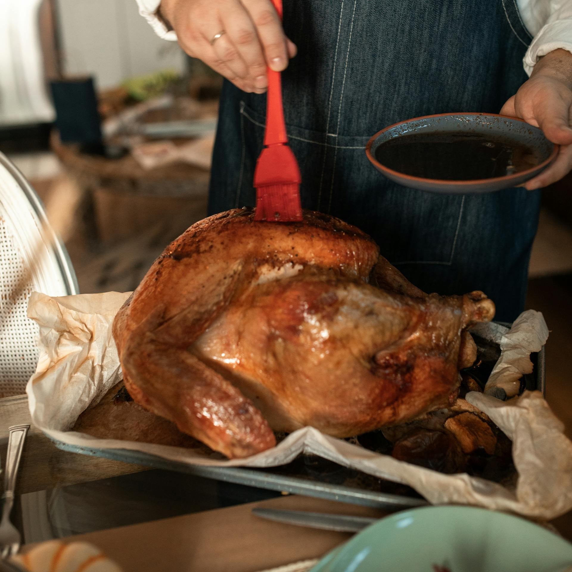 Person preparing a roasted turkey in a kitchen setting