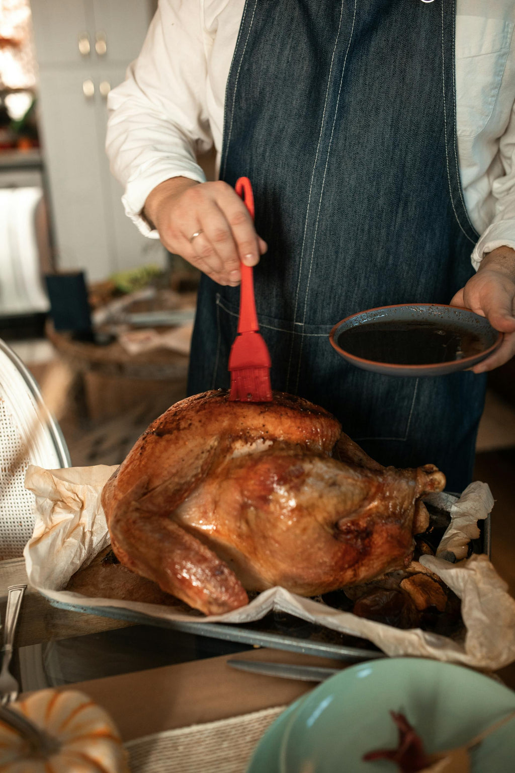 Person preparing a roasted turkey in a kitchen setting